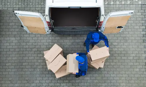 Men Unloading Cardboard Boxes From Delivery Truck